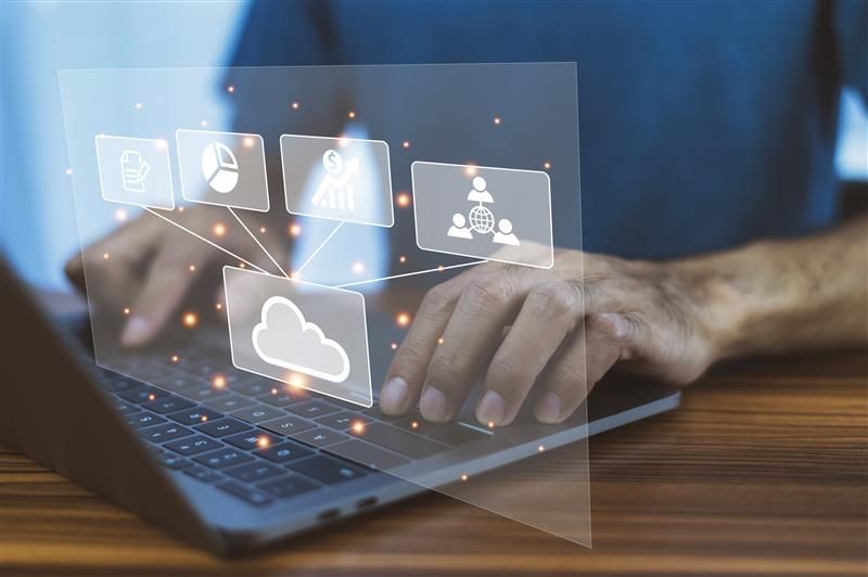 A person typing on a laptop with holographic icons representing cloud-based intranet ROI metrics.