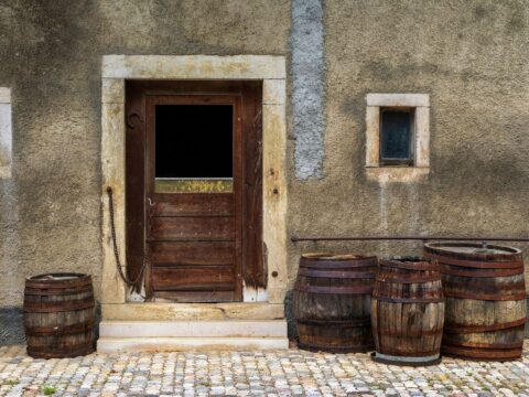 Rustic timber door and wooden barrels outside an old stone building